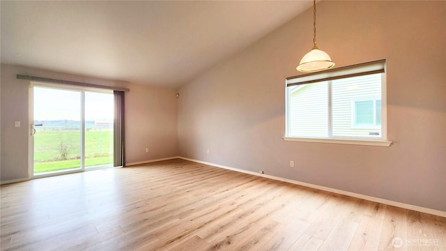 spare room with baseboards, light wood-type flooring, and lofted ceiling