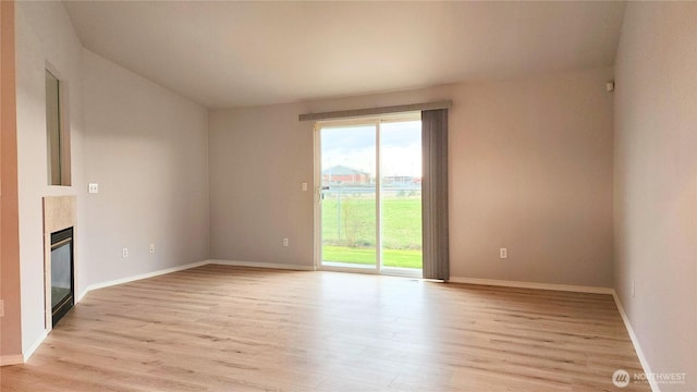 unfurnished living room with light wood finished floors, a fireplace, and baseboards