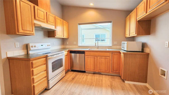 kitchen featuring under cabinet range hood, a sink, recessed lighting, white appliances, and light wood finished floors