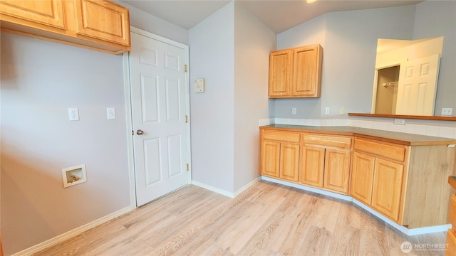 kitchen featuring baseboards, light brown cabinetry, light countertops, a peninsula, and light wood-style floors