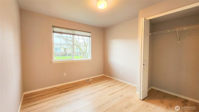 unfurnished bedroom with a closet, baseboards, visible vents, and wood finished floors