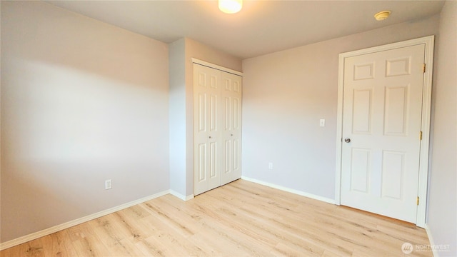 unfurnished bedroom with a closet, light wood-style flooring, and baseboards