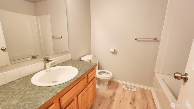 bathroom featuring vanity, wood finished floors, visible vents, baseboards, and toilet