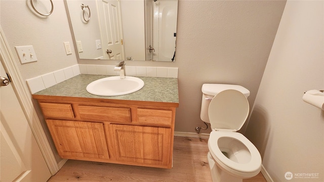 bathroom featuring toilet, vanity, baseboards, and wood finished floors