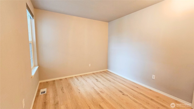 unfurnished room featuring visible vents, baseboards, and wood finished floors