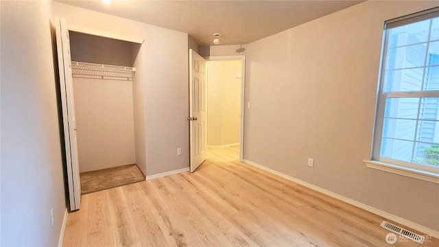 unfurnished bedroom featuring a closet, visible vents, baseboards, and wood finished floors