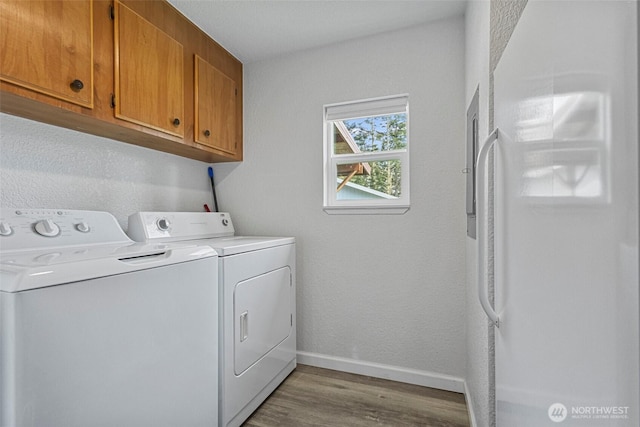 washroom featuring baseboards, cabinet space, independent washer and dryer, and light wood-style flooring