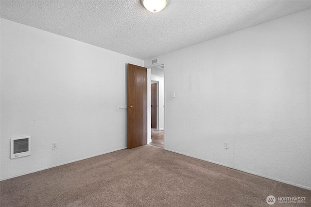 empty room with visible vents, carpet floors, a textured ceiling, and heating unit