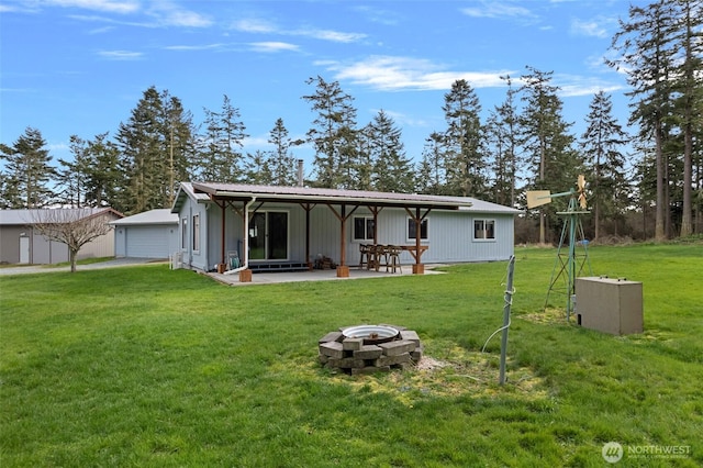 back of house featuring a yard, a patio, a fire pit, and a garage