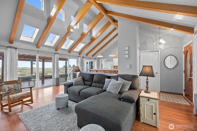 living room with a skylight, beam ceiling, and light wood-style flooring