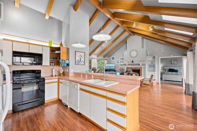 kitchen featuring dark wood-style floors, a peninsula, a sink, black appliances, and open floor plan