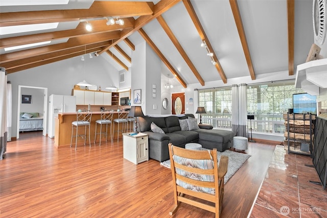 living area with a skylight, light wood-style floors, and beamed ceiling