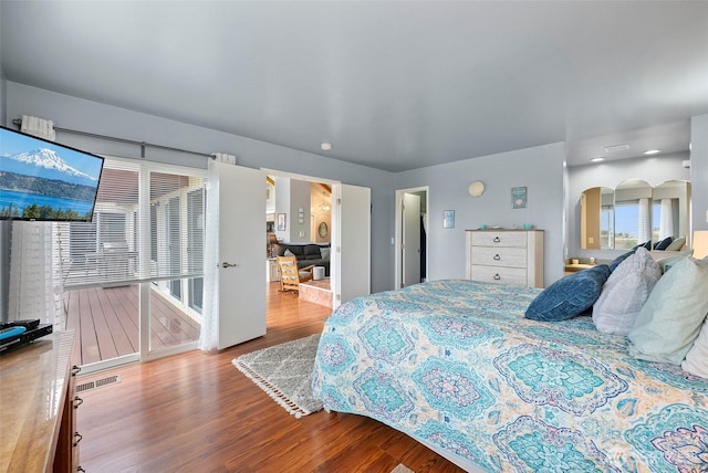 bedroom featuring visible vents, arched walkways, and wood finished floors