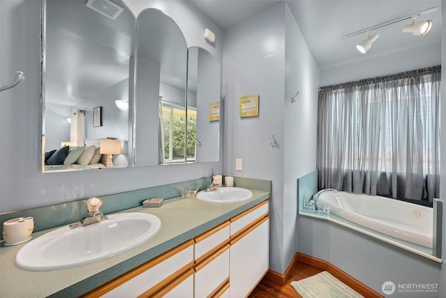 full bathroom featuring a sink, visible vents, wood finished floors, and double vanity