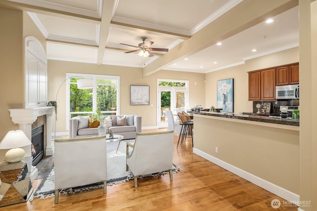 living room featuring recessed lighting, light wood-type flooring, beam ceiling, a glass covered fireplace, and ceiling fan