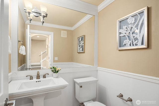 bathroom with visible vents, toilet, ornamental molding, a sink, and a notable chandelier