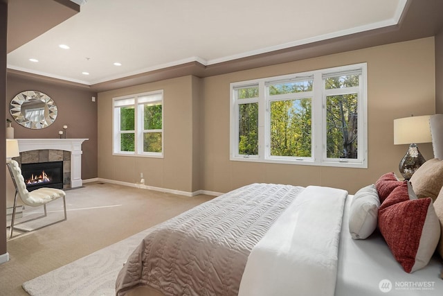 bedroom featuring a tray ceiling, a tiled fireplace, baseboards, recessed lighting, and carpet floors