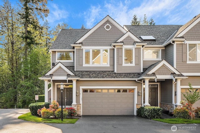 view of front facade featuring an attached garage, a shingled roof, driveway, and stone siding