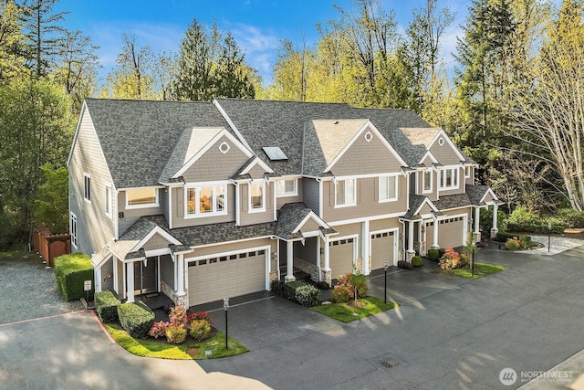 view of front of property with an attached garage, roof with shingles, and driveway