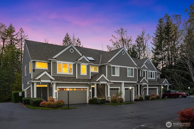 townhome / multi-family property with an attached garage, aphalt driveway, and roof with shingles