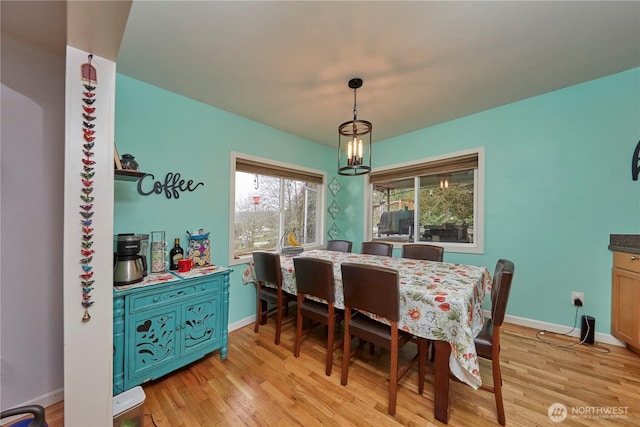 dining area featuring baseboards, an inviting chandelier, and light wood finished floors