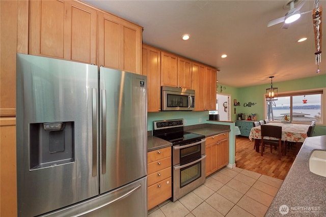 kitchen featuring dark countertops, recessed lighting, stainless steel appliances, light tile patterned floors, and hanging light fixtures