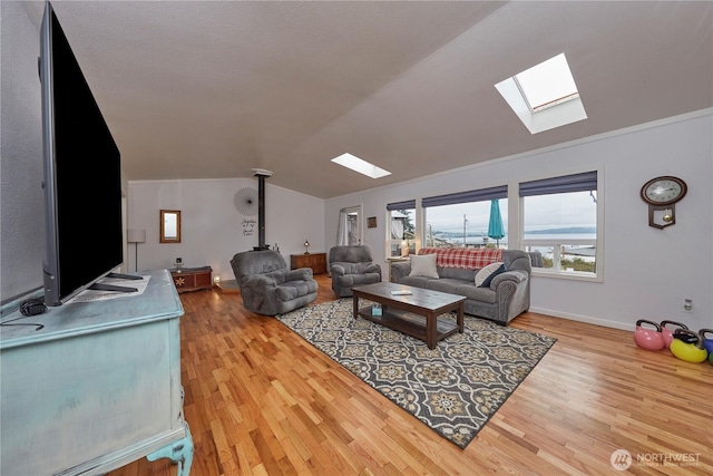 living room with lofted ceiling with skylight, wood finished floors, and baseboards