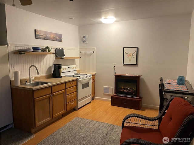 kitchen with a sink, visible vents, light wood-style floors, and white range with electric stovetop