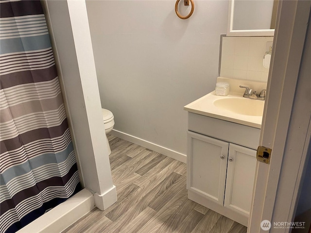 full bath with vanity, wood finished floors, baseboards, decorative backsplash, and toilet