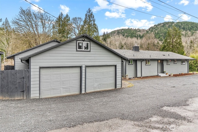 ranch-style home with fence, a chimney, driveway, a garage, and a mountain view