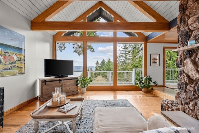 living area with beamed ceiling, a healthy amount of sunlight, and wood finished floors