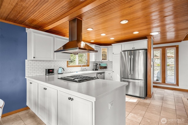 kitchen featuring tasteful backsplash, appliances with stainless steel finishes, island exhaust hood, a peninsula, and white cabinetry