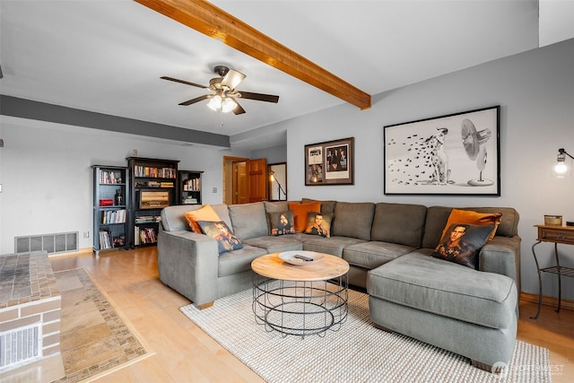 living area with visible vents, beamed ceiling, ceiling fan, and light wood finished floors