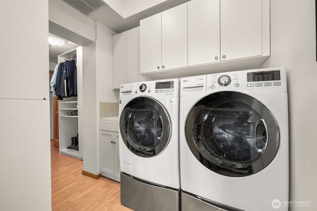 washroom featuring cabinet space, visible vents, independent washer and dryer, and light wood-type flooring