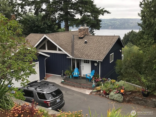 view of front facade featuring a chimney, board and batten siding, a shingled roof, and a garage