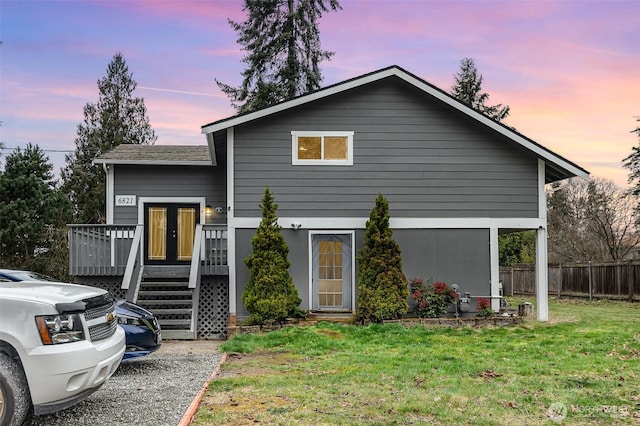 view of front of house with fence, stairway, a wooden deck, french doors, and a yard