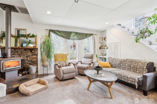 carpeted living area featuring stairs, a wood stove, recessed lighting, and visible vents