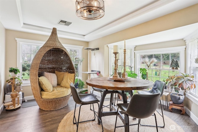 dining space with visible vents, baseboards, a tray ceiling, and wood finished floors