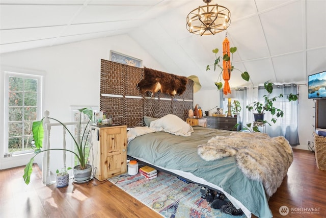 bedroom with a chandelier, lofted ceiling, and wood finished floors