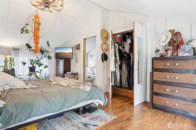 bedroom featuring a walk in closet, ensuite bathroom, wood finished floors, a closet, and vaulted ceiling