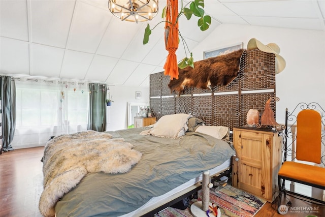 bedroom with a chandelier, wood finished floors, and vaulted ceiling