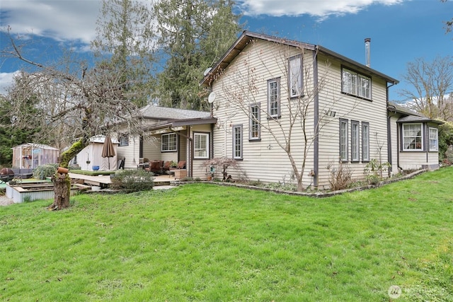 back of property featuring an outbuilding, a vegetable garden, a lawn, and a patio