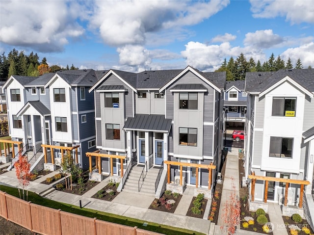 townhome / multi-family property featuring a standing seam roof, board and batten siding, a residential view, and metal roof