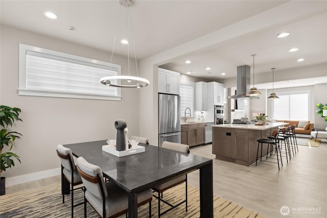 dining space featuring light wood finished floors, recessed lighting, and baseboards