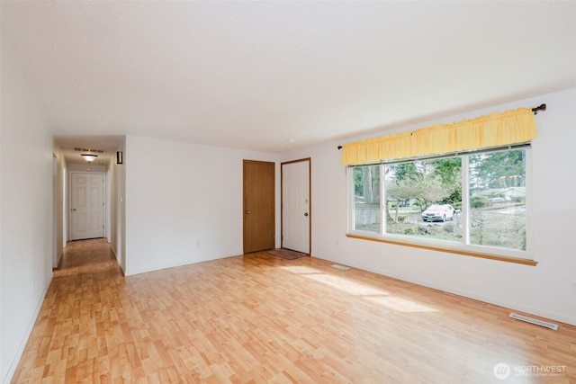 unfurnished room featuring light wood-type flooring and visible vents