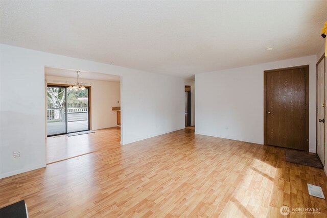 spare room with visible vents, light wood-style floors, and a chandelier