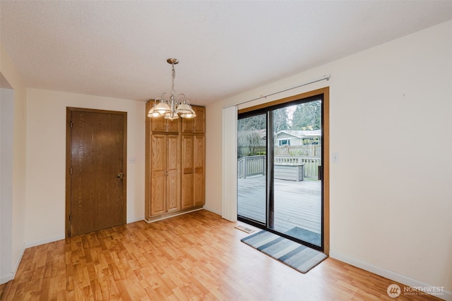 doorway to outside with baseboards, light wood-style floors, visible vents, and a chandelier