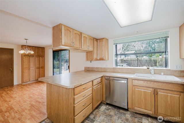 kitchen with stainless steel dishwasher, a peninsula, light countertops, and a sink