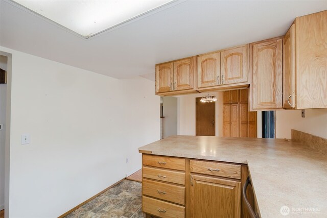 kitchen featuring baseboards, a peninsula, light brown cabinets, and light countertops