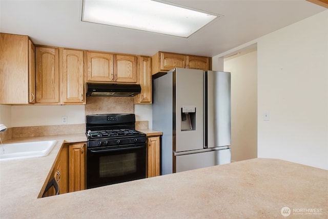 kitchen featuring stainless steel refrigerator with ice dispenser, under cabinet range hood, a sink, black gas range oven, and light countertops